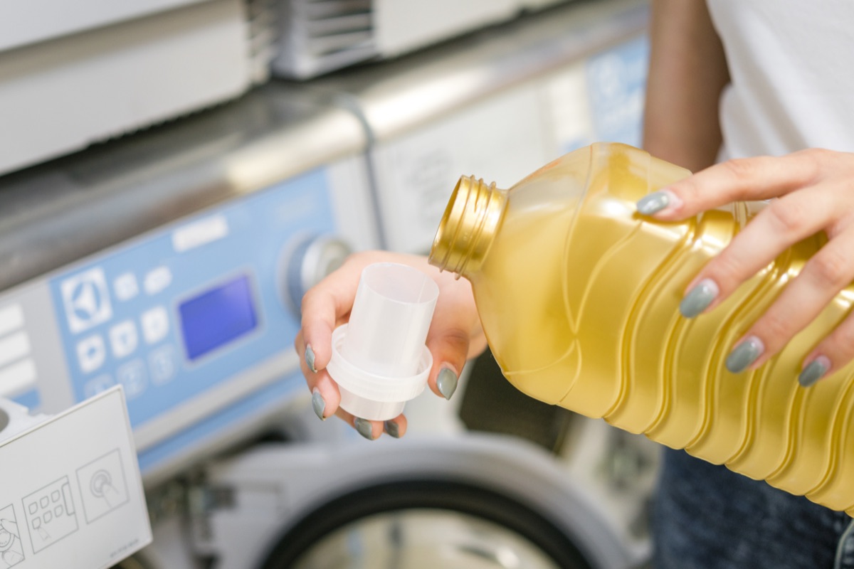 Liquid detergent being poured into a measuring cap at a washing machine